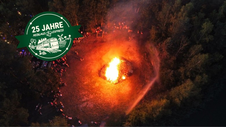 Sommersonnenwende in Langau, © Marktgemeinde Langau Luftaufnahme eines großen Sonnwendfeuer in einem Waldgebiet mit Menschen drumherum.