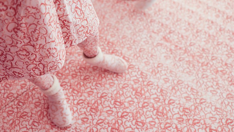 Die Kunstperformance, © Valerie Habsburg Person in rosa gemustertem Outfit steht auf einem Boden mit demselben Muster.