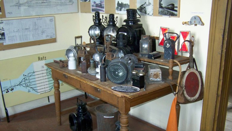 Ausstellung im Museum, © Alfred Schmid Ein Tisch mit alten Eisenbahnlampen und Signalen in einem Raum mit historischen Plänen an der Wand.