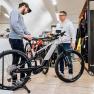 Two men look at a bicycle in a bicycle store.