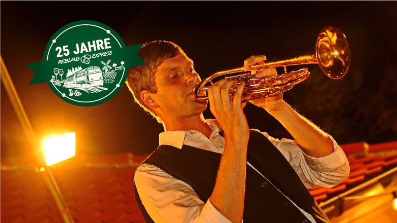 Ein Mann spielt Trompete bei Nacht.