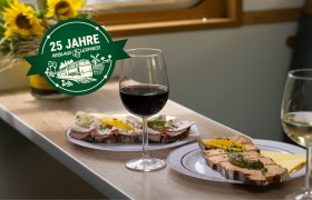 Zwei Weingl&auml;ser und belegte Brote auf einem Tisch in einem Zugabteil.