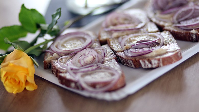 Aufstrichbrot mit Zwiebeln, daneben gelbe Rose