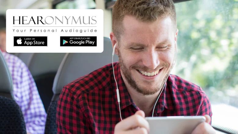 Ein Mann hört mit Kopfhörern den Hearonymus-Audioguide auf einem Tablet; daneben sind Hinweise zum App Store und zu Google Play eingeblendet.