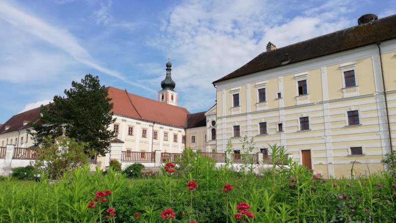 Stift Geras mit Garten und blühenden Blumen im Vordergrund.