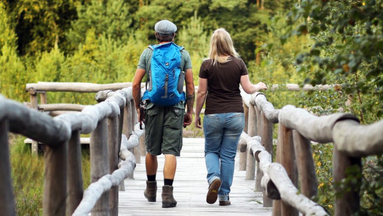 zwei Personen gehen über Holzbrücke