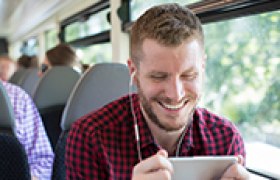 Mann hört Audioguide mit Kopfhörern im Zug