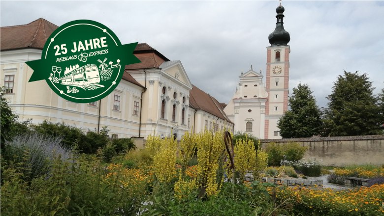 Ein historisches Geb&auml;ude mit einem Turm im Hintergrund und einem Garten im Vordergrund.