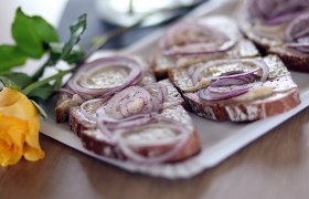 Aufstrichbrot mit Zwiebeln, daneben gelbe Rose