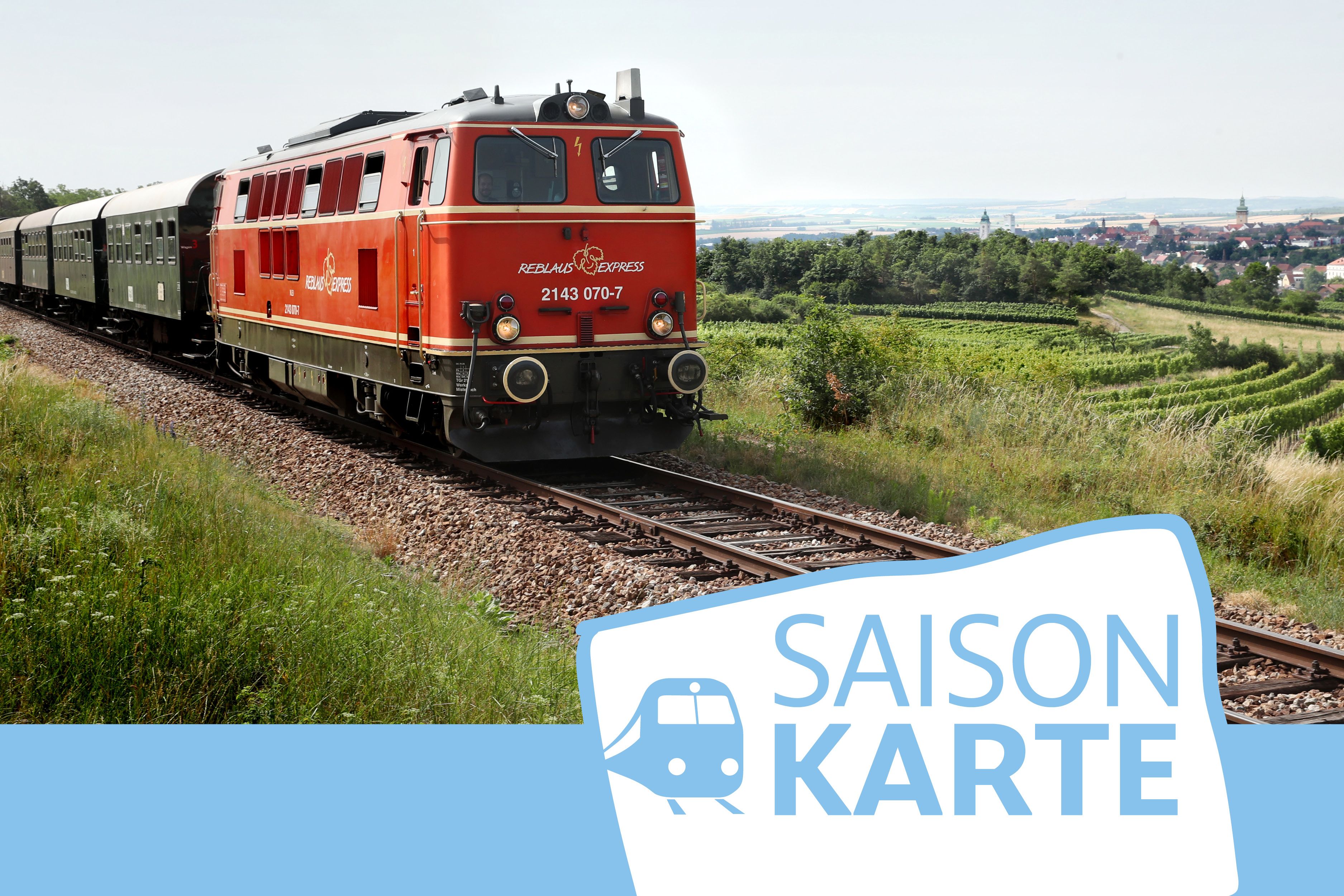 Ein roter Zug fährt durch eine ländliche Landschaft mit Feldern und einem Dorf im Hintergrund. Unten rechts ist das Logo 'Saisonkarte' zu sehen.