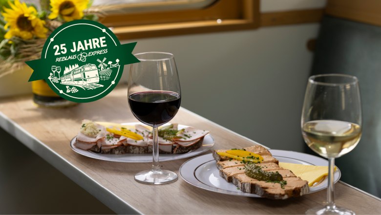 Zwei Weingl&auml;ser und belegte Brote auf einem Tisch in einem Zugabteil.