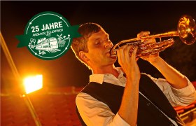 Ein Mann spielt Trompete bei Nacht.