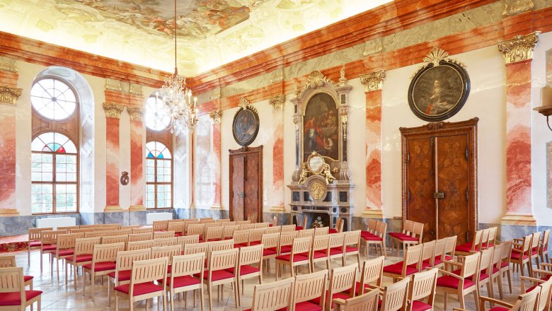 Innenansicht eines prunkvollen Barocksaals mit Stuckdecke und Kronleuchter im Stift Geras.