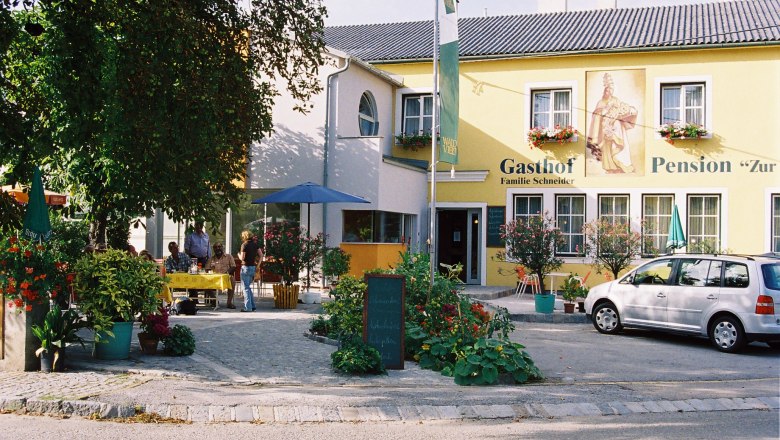 Gasthof-Pension "Zur Hammerschmiede", © Ludwig Schneider Ein gelbes Gebäude mit der Aufschrift 'Gasthof-Pension Zur Hammerschmiede'. Vor dem Gebäude stehen Tische, Stühle und ein Auto.