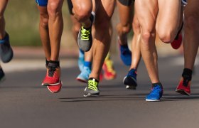 L&auml;uferbeine in bunten Sportschuhen auf einer Stra&szlig;e w&auml;hrend eines Rennens.