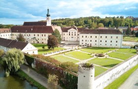 Luftaufnahme des Stifts Geras mit Garten und Turm im Vordergrund.