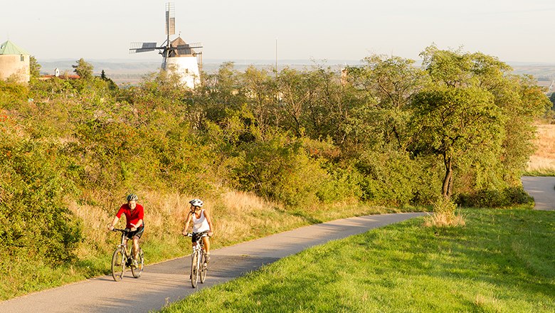 Radfahrer fahren an Windmühle vorbei