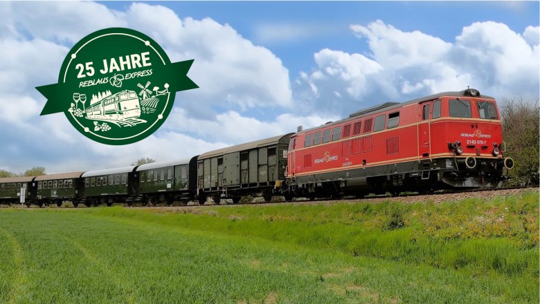 Roter Zug mit mehreren Waggons f&auml;hrt auf Gleisen durch eine gr&uuml;ne Landschaft unter blauem Himmel, daneben gr&uuml;nes Jubil&auml;umslogo