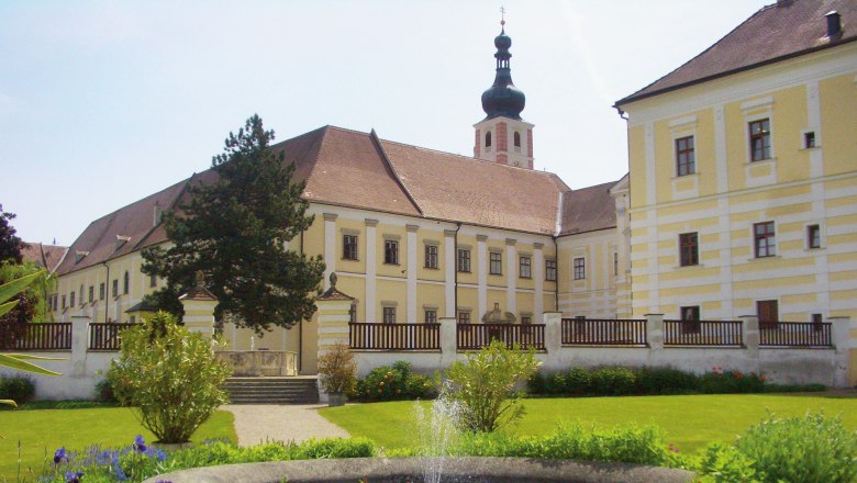 Historisches Klostergebäude mit Garten und Springbrunnen.