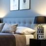 Elegant double room with gray headboard, two pillows, bedside lamp and wall pictures.
